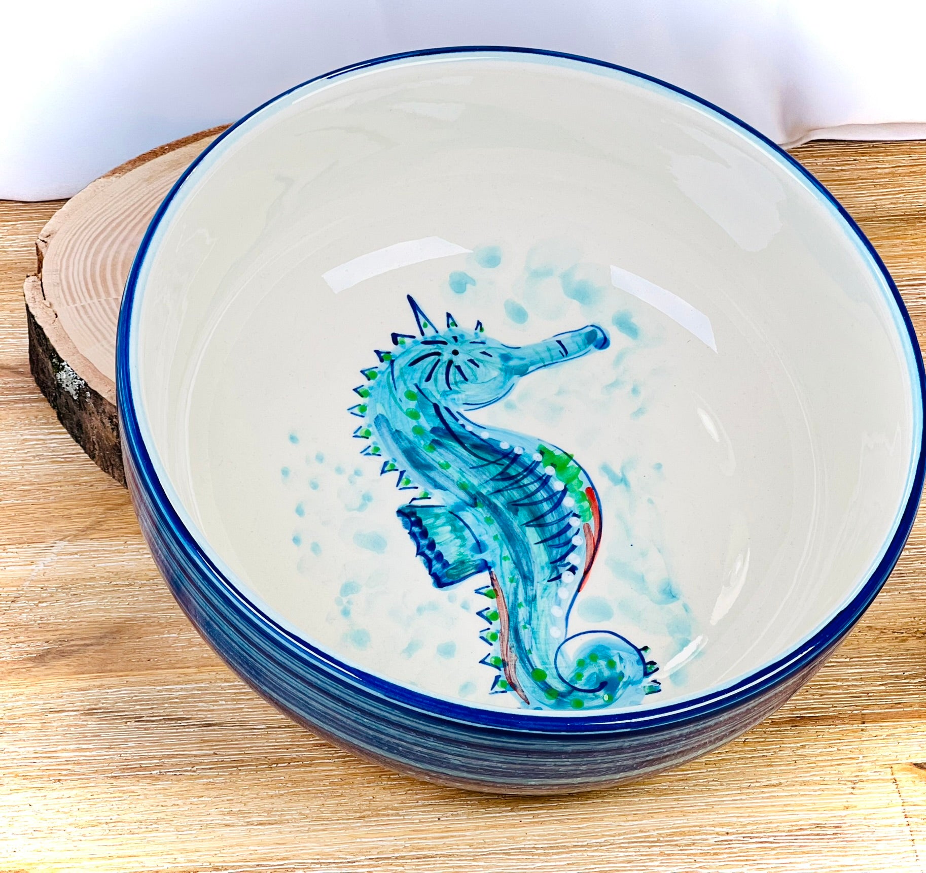 Handgemachte Keramikschale (23 cm) mit außen leuchtend blauer Glasur und handgemaltem Seepferdchen-Motiv in Blau-, Türkis- und Grüntönen, feinen Details und geschwungenen Linien auf weißem Grund.