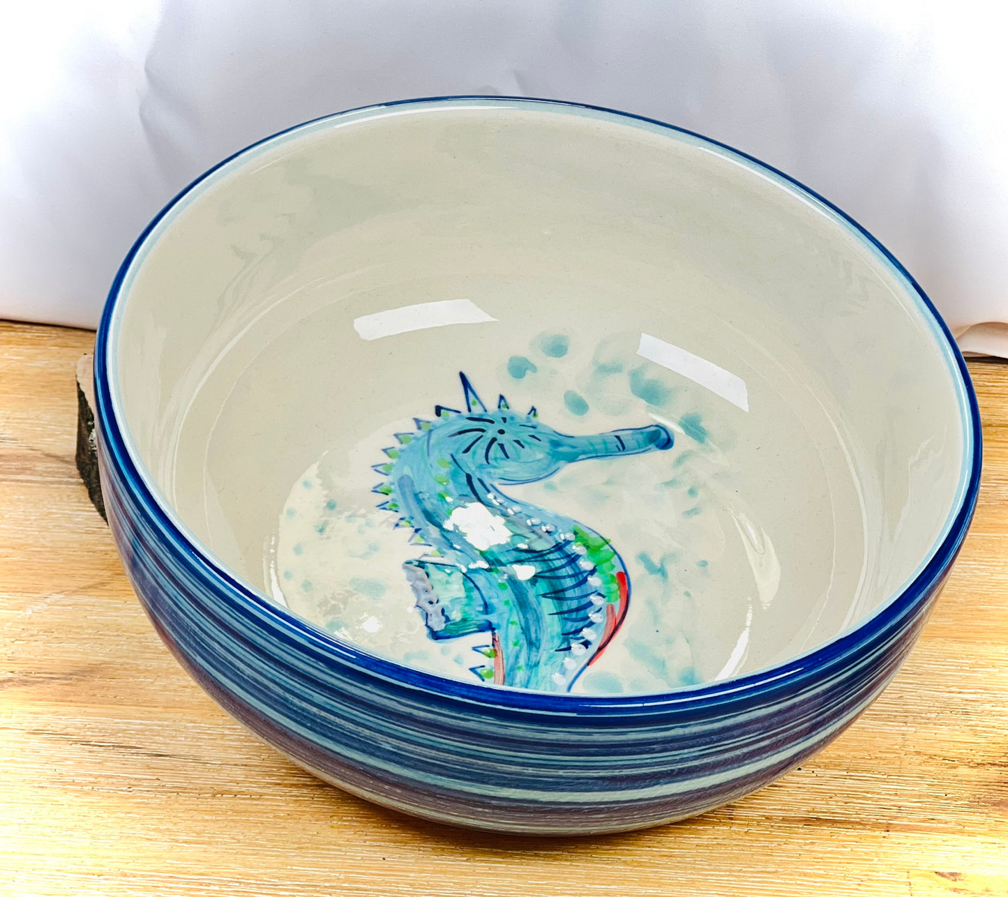Handgemachte Keramikschale (23 cm) mit außen leuchtend blauer Glasur und handgemaltem Seepferdchen-Motiv in Blau-, Türkis- und Grüntönen, feinen Details und geschwungenen Linien auf weißem Grund.