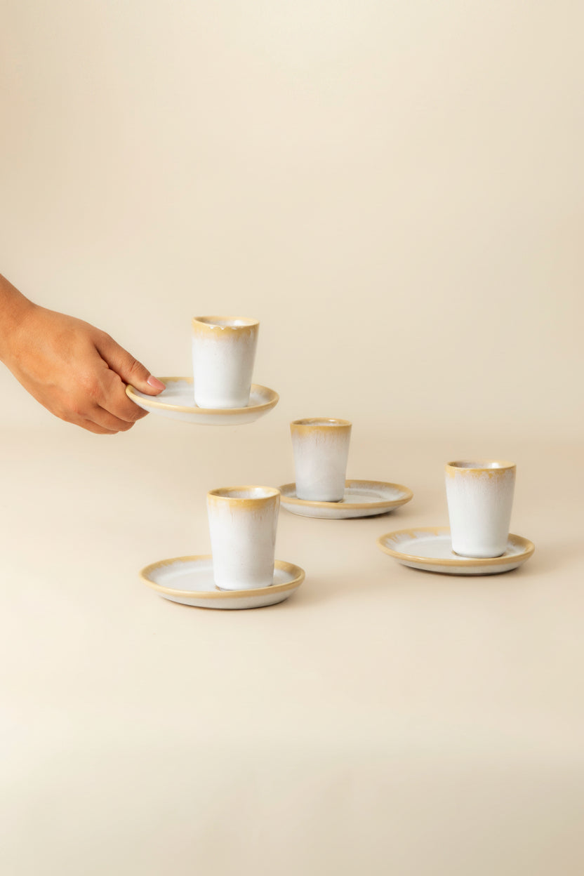 Terrafina Amazonia Espresso-Tasse mit Untertasse in Weiß – in der Hand gehalten, im Hintergrund weitere Sets, handgefertigt in Portugal