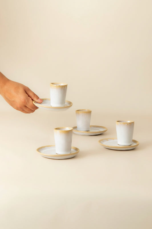 Terrafina Amazonia Espresso-Tasse mit Untertasse in Weiß – in der Hand gehalten, im Hintergrund weitere Sets, handgefertigt in Portugal